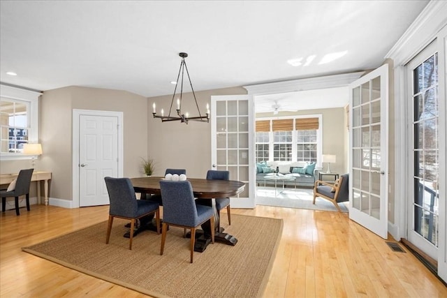 dining room featuring visible vents, baseboards, light wood-style flooring, an inviting chandelier, and french doors