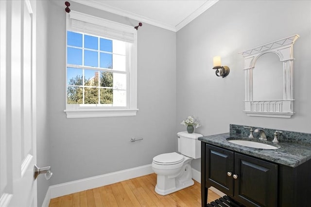 half bathroom with baseboards, toilet, ornamental molding, wood finished floors, and vanity