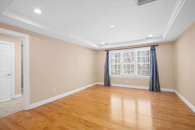 unfurnished room with ornamental molding, light wood-type flooring, a raised ceiling, and baseboards