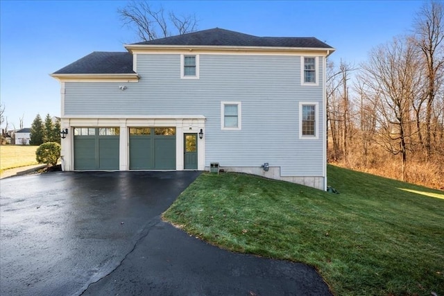 view of front facade with aphalt driveway, a front yard, and an attached garage