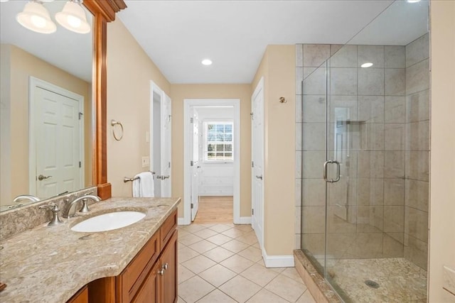 bathroom with tile patterned floors, a shower stall, vanity, and baseboards