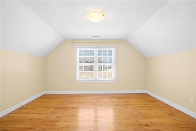 bonus room featuring light wood-style floors, visible vents, vaulted ceiling, and baseboards