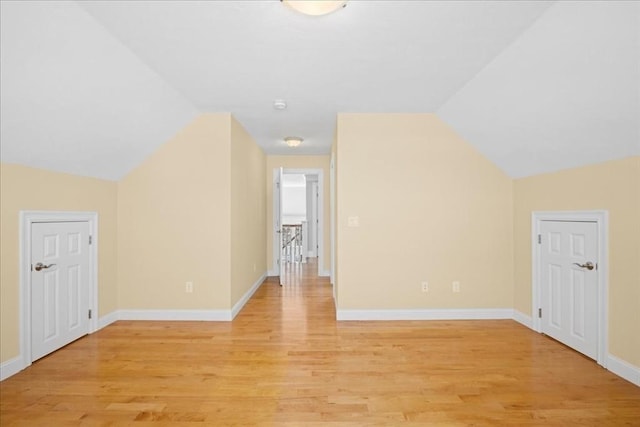 additional living space featuring light wood-style flooring, baseboards, and vaulted ceiling