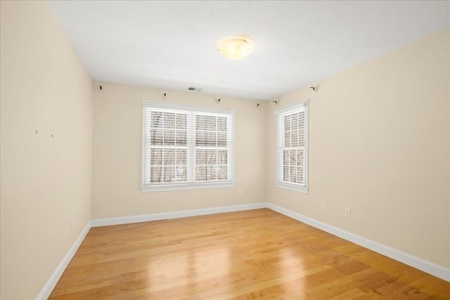 spare room with visible vents, light wood-style flooring, and baseboards