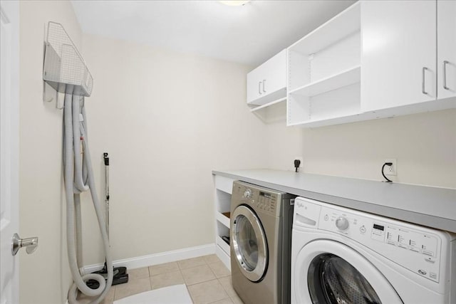 clothes washing area featuring light tile patterned floors, baseboards, separate washer and dryer, and cabinet space