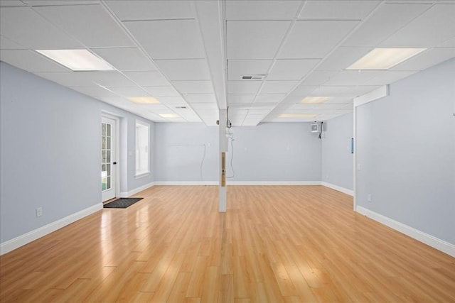 below grade area with a drop ceiling, light wood-style flooring, and baseboards