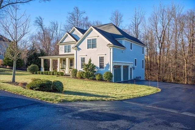 view of front facade featuring covered porch, aphalt driveway, a front yard, and an attached garage