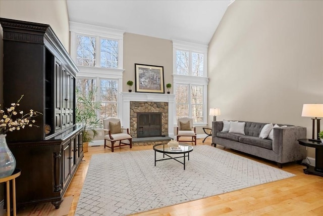 living area with high vaulted ceiling, a fireplace, baseboards, and wood finished floors