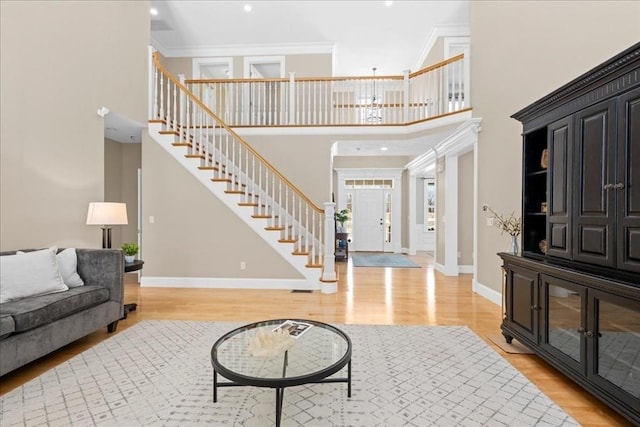 foyer with light wood-style flooring, stairs, baseboards, and ornamental molding