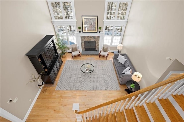 living room featuring stairway, wood finished floors, a wealth of natural light, and a glass covered fireplace