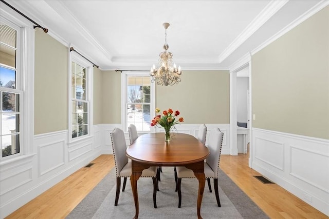 dining room featuring a chandelier, light wood-type flooring, visible vents, and crown molding