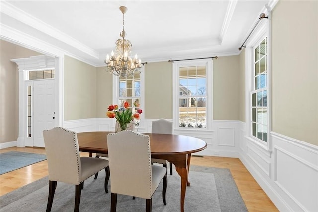 dining space with a chandelier, wainscoting, ornamental molding, and light wood-type flooring