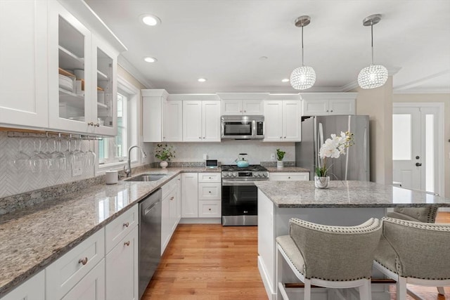 kitchen featuring sink, stainless steel appliances, a breakfast bar, and white cabinets