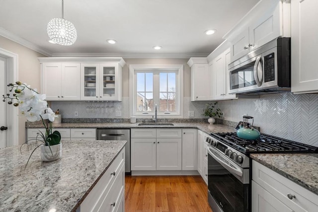 kitchen featuring sink, appliances with stainless steel finishes, white cabinetry, and hanging light fixtures