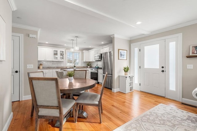 dining space with crown molding and light hardwood / wood-style flooring