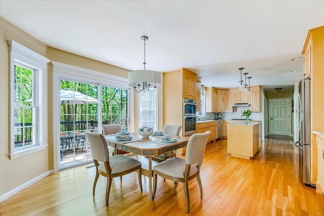 dining room with a chandelier, light wood-style flooring, and baseboards