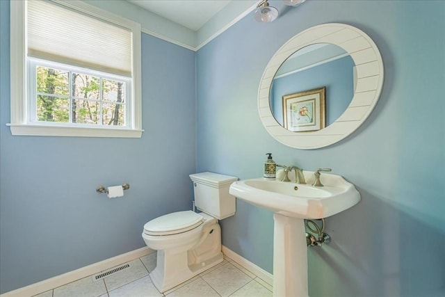 bathroom with toilet, baseboards, and tile patterned flooring