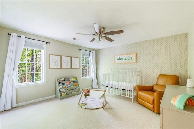 bedroom featuring baseboards, a nursery area, carpet flooring, and ceiling fan
