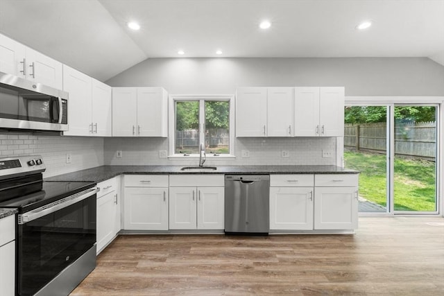 42 Deer Hollow Rd, Sandwich, MA 02644 - kitchen with stainless steel appliances, lofted ceiling, light wood finished floors, white cabinetry, and decorative backsplash