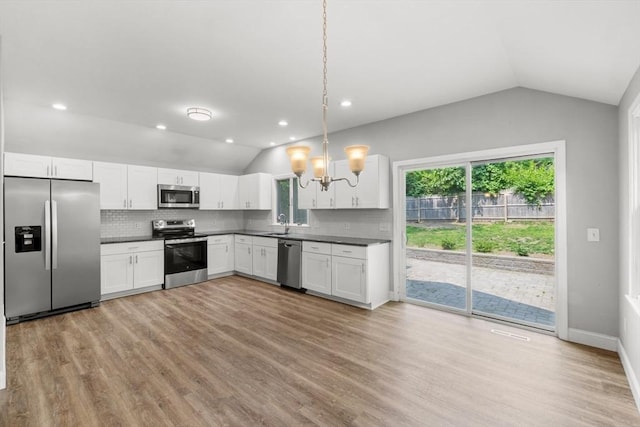 42 Deer Hollow Rd, Sandwich, MA 02644 - kitchen featuring appliances with stainless steel finishes, lofted ceiling, dark countertops, a chandelier, and decorative backsplash