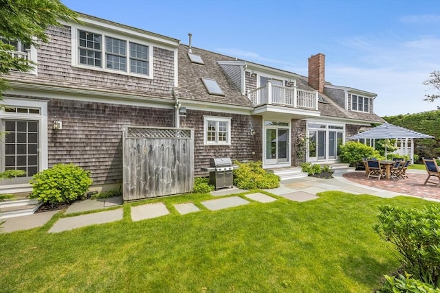 86 Champlain, Chatham, MA 02633 - back of house featuring a balcony, a lawn, entry steps, a patio area, and a chimney