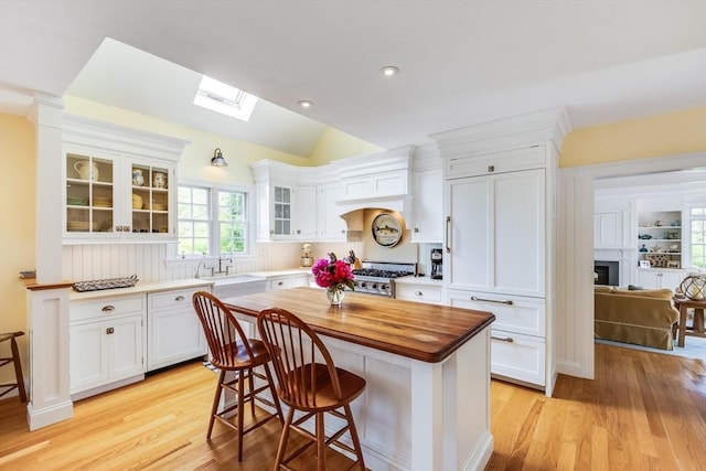 86 Champlain, Chatham, MA 02633 - kitchen with butcher block countertops, white cabinetry, light wood finished floors, vaulted ceiling, and recessed lighting