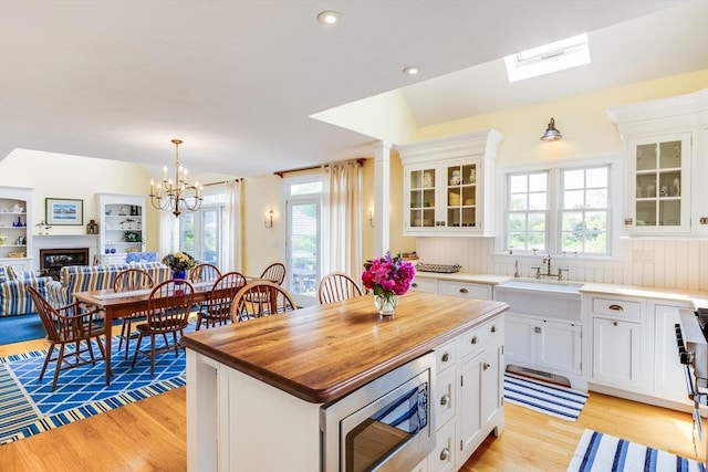 86 Champlain, Chatham, MA 02633 - kitchen with stainless steel microwave, light wood finished floors, butcher block countertops, white cabinets, and recessed lighting