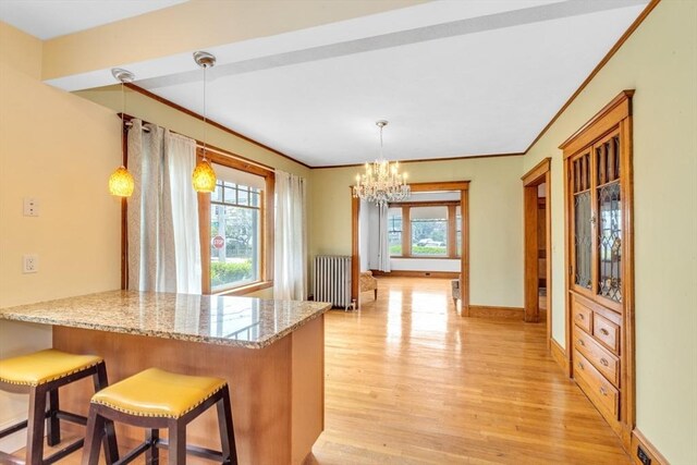 17 Matchett St, Boston, MA 02135 - kitchen featuring light wood-type flooring, a chandelier, radiator heating unit, a peninsula, and crown molding
