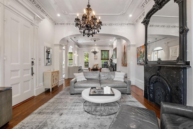 living room featuring arched walkways, a chandelier, wood-type flooring, decorative columns, and ornamental molding