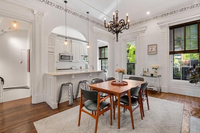 dining space with a chandelier, wood-type flooring, recessed lighting, and arched walkways