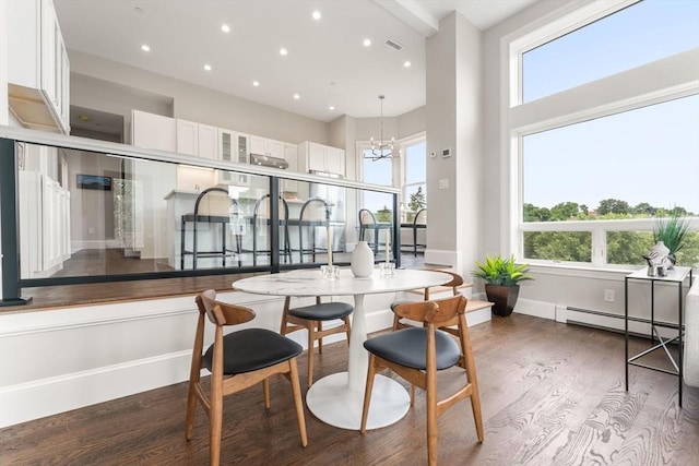 interior space with a high ceiling, dark hardwood / wood-style flooring, a baseboard heating unit, and a notable chandelier