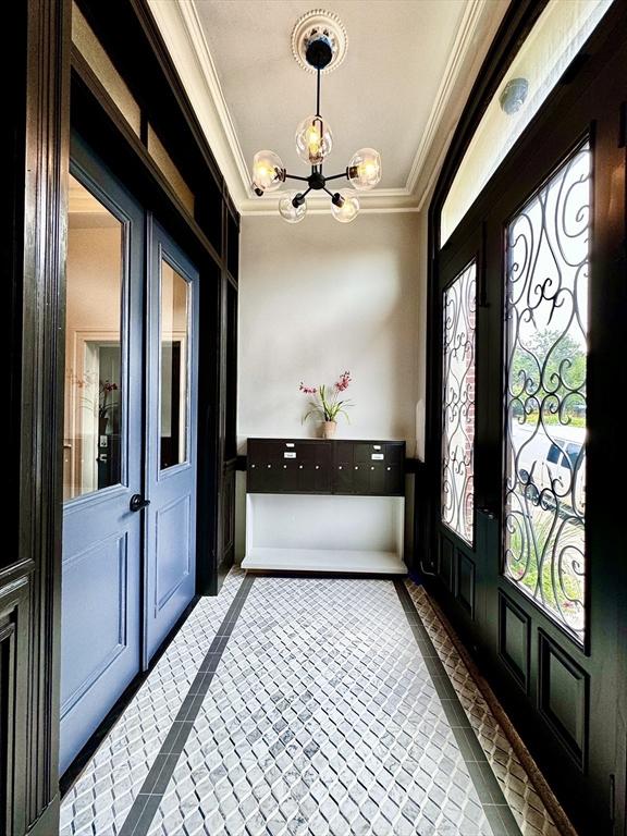 foyer featuring a chandelier, french doors, and crown molding