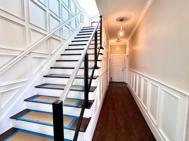 stairs with wood-type flooring and crown molding