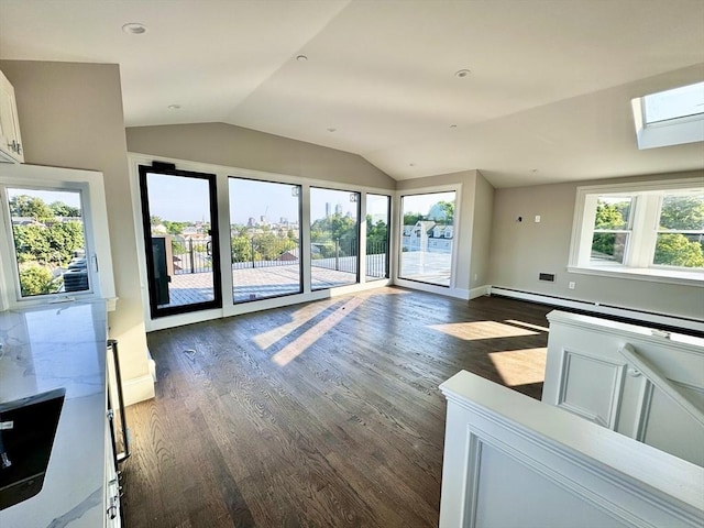 unfurnished living room featuring vaulted ceiling with skylight, dark hardwood / wood-style flooring, a wealth of natural light, and a baseboard radiator