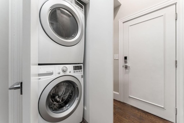 washroom with stacked washer and dryer and dark wood-type flooring