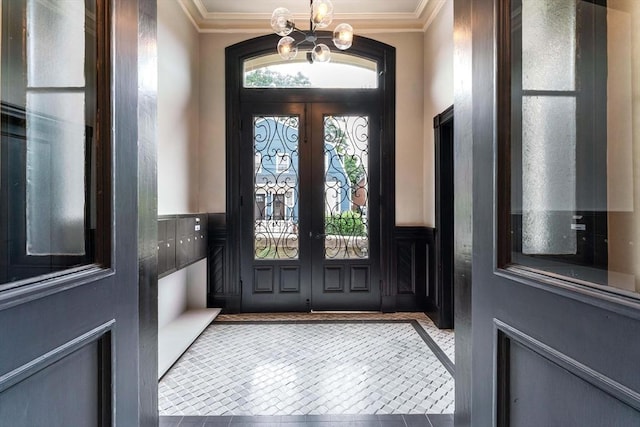 tiled entrance foyer with a chandelier, french doors, and ornamental molding