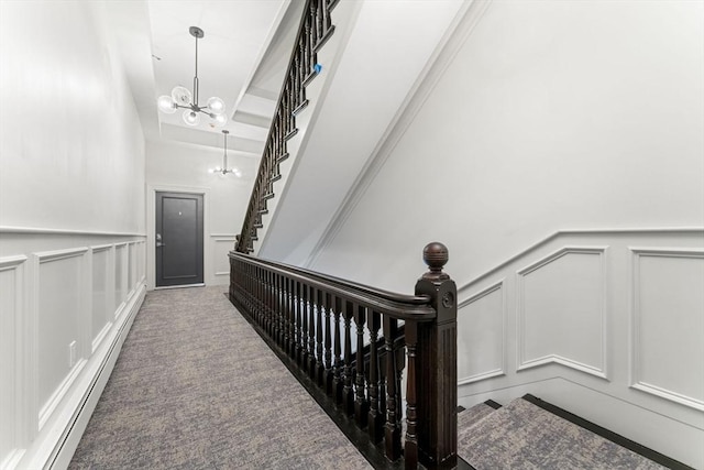 stairs featuring carpet flooring, a baseboard heating unit, and a notable chandelier