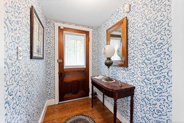 foyer with baseboards, wood finished floors, and wallpapered walls