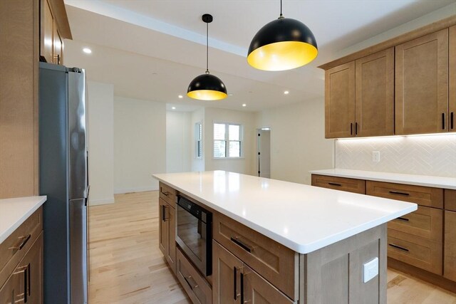 59 Dartmouth St Unit B, Somerville, MA 02145 - kitchen featuring appliances with stainless steel finishes, light wood-type flooring, decorative backsplash, hanging light fixtures, and a kitchen island