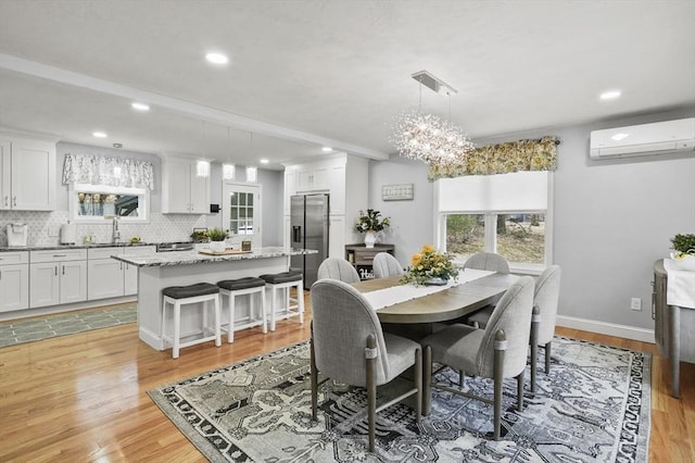 dining area with a wall unit AC, recessed lighting, light wood-type flooring, and baseboards