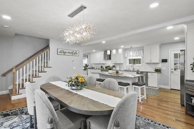 dining space with light wood-type flooring, recessed lighting, baseboards, a chandelier, and stairs