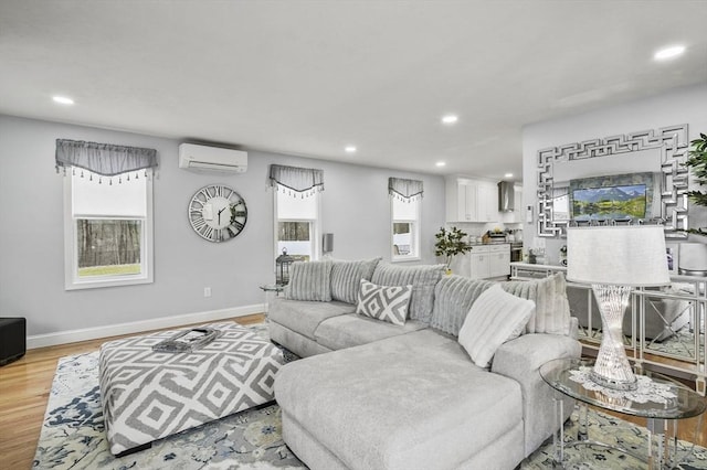 living area with a wall unit AC, plenty of natural light, light wood-style floors, and recessed lighting