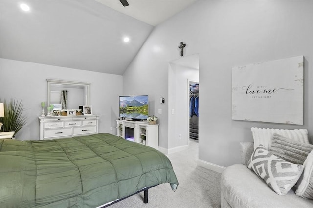 bedroom featuring a walk in closet, baseboards, lofted ceiling, light carpet, and a closet