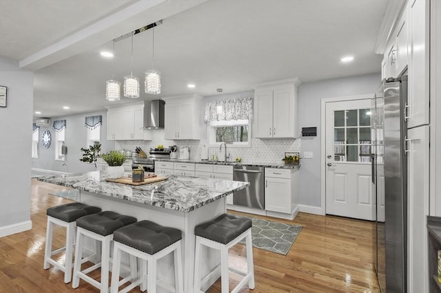 kitchen with tasteful backsplash, appliances with stainless steel finishes, wall chimney exhaust hood, and a kitchen bar