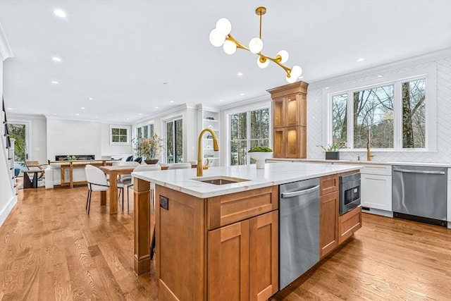 kitchen featuring a sink, open floor plan, appliances with stainless steel finishes, light wood-type flooring, and crown molding