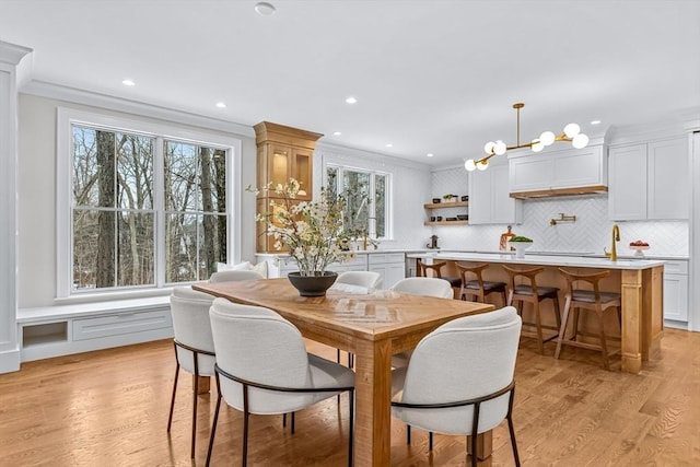 dining area with light wood-style flooring, ornamental molding, and recessed lighting