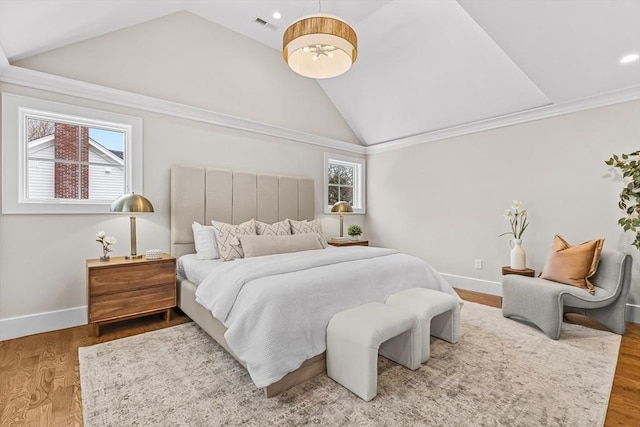 bedroom with multiple windows, vaulted ceiling, baseboards, and wood finished floors