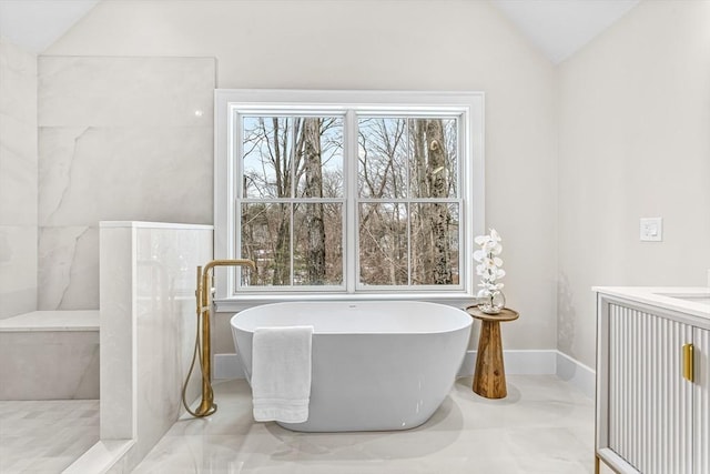 full bath with a wealth of natural light, vaulted ceiling, and a freestanding bath