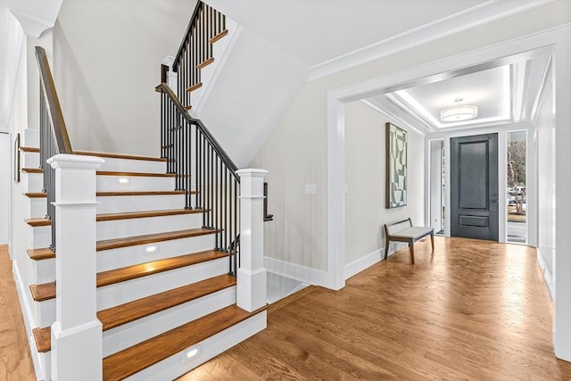 entryway featuring ornamental molding, stairway, baseboards, and wood finished floors