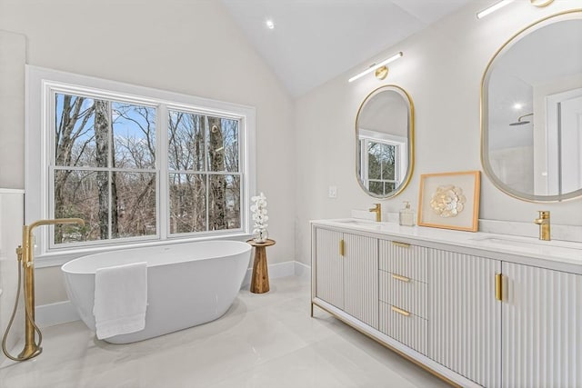 bathroom featuring lofted ceiling, a freestanding tub, plenty of natural light, and a sink